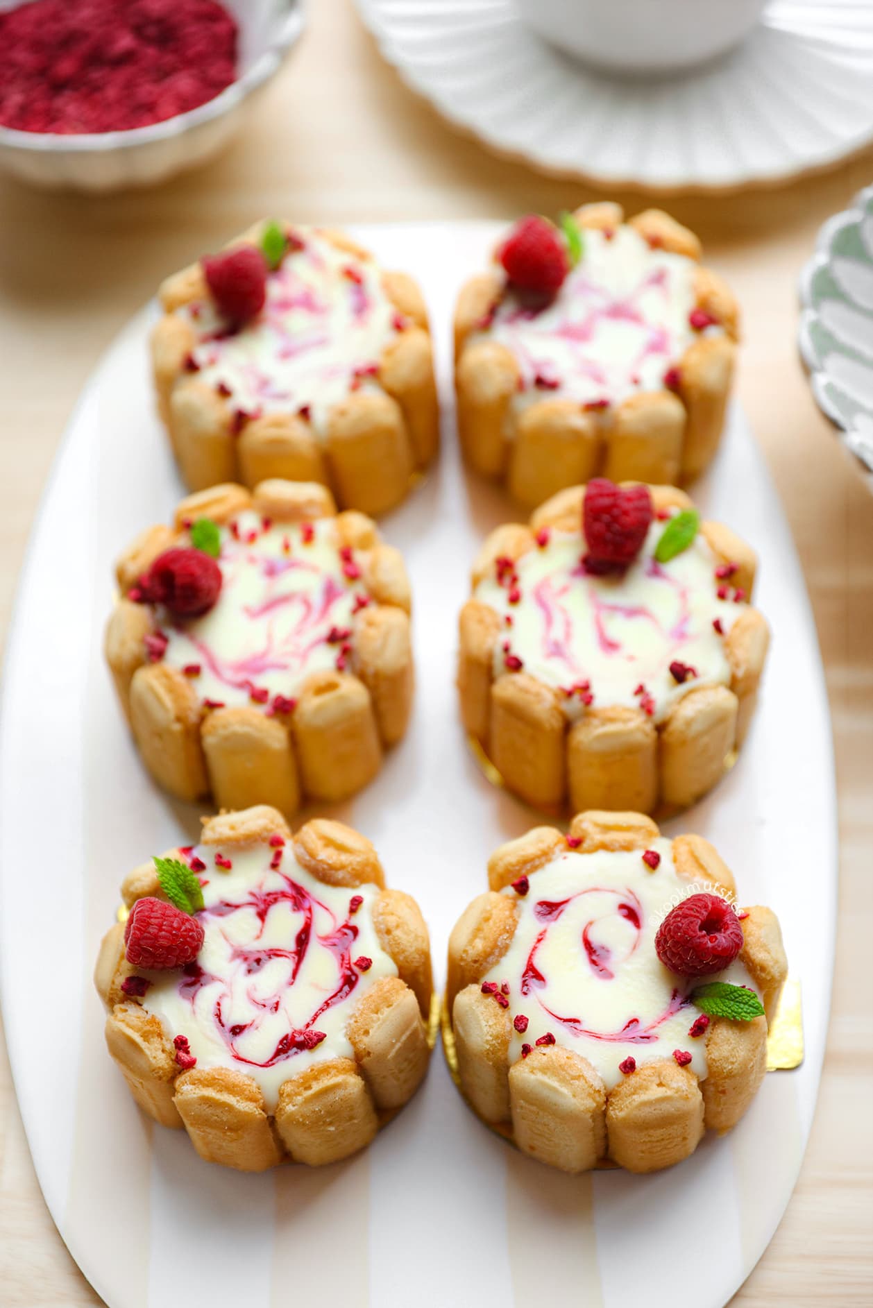 Kleine charlotte taartjes met lange vingers, frambozen en witte chocoladetopping
