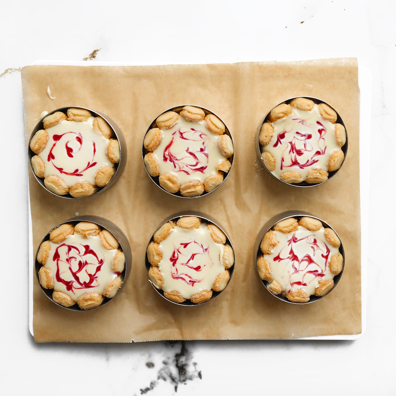 Afgewerkte mini frambozen charlotte taartjes met lange vingers en witte chocoladetopping